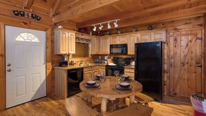A wooden cabin kitchen with a dining table set for four, wooden cabinets, a microwave, and a refrigerator. - Unforgettable Luxury Mountain Getaway (PIGEON FORGE)