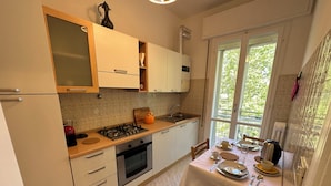 Cocina compacta con zona de comedor, que incluye estufa, horno y ventana con vistas a zonas verdes.