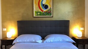 A bed with white linens, a dark headboard, and two bedside lamps. - Gian House - centro città (Rimini)