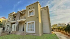 A modern two-story residential building with a flat roof, balconies, and a well-maintained lawn. - Settle Inn Cairo Festival City Villa (New Cairo)