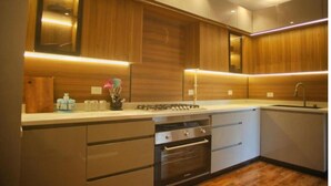 A modern kitchen with wooden cabinets, a built-in oven, and a stainless steel sink. - Settle Inn Cairo Festival City Villa (New Cairo)