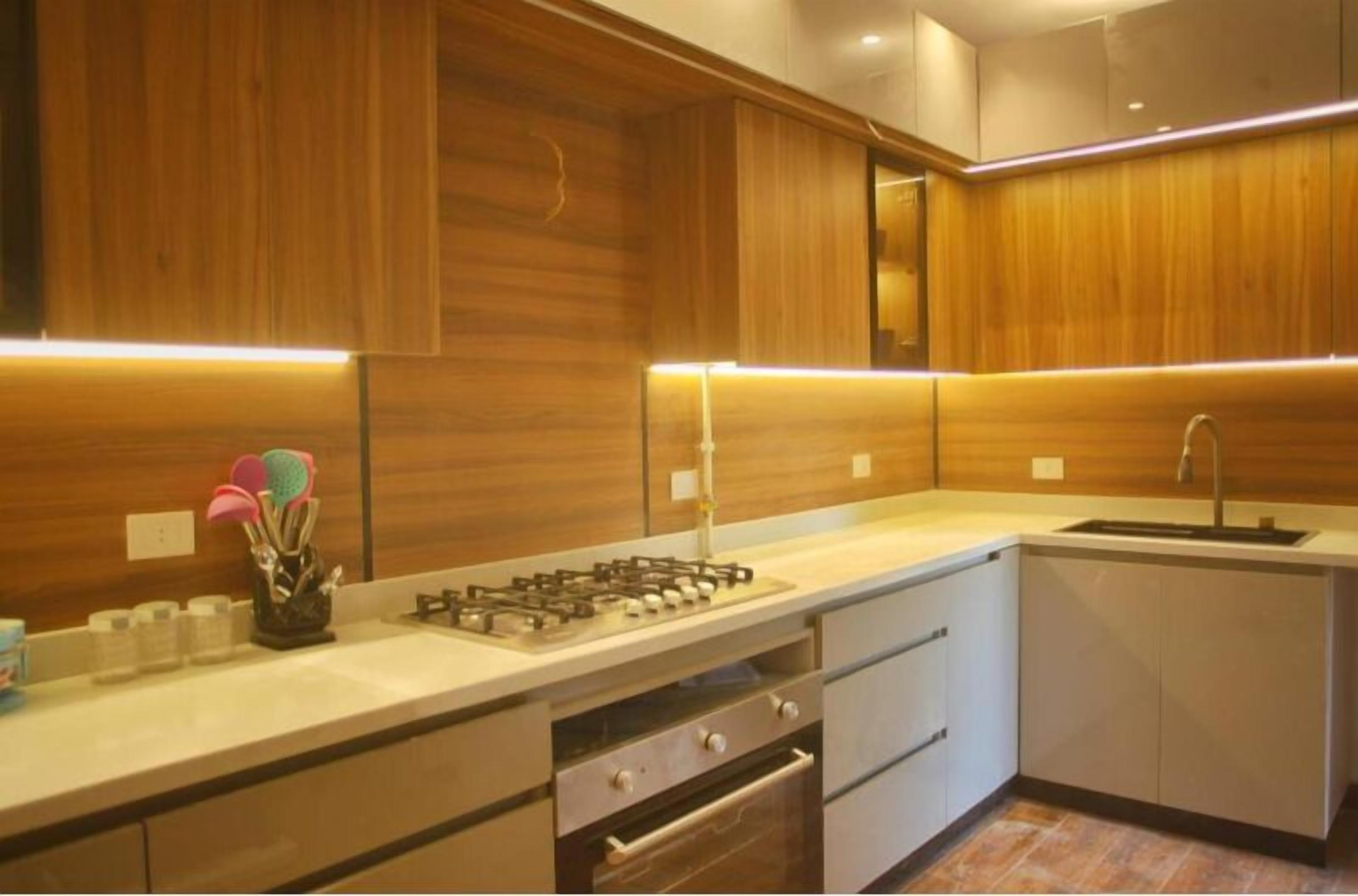 A modern kitchen with wooden cabinetry, a gas stove, a sink, and a built-in oven.