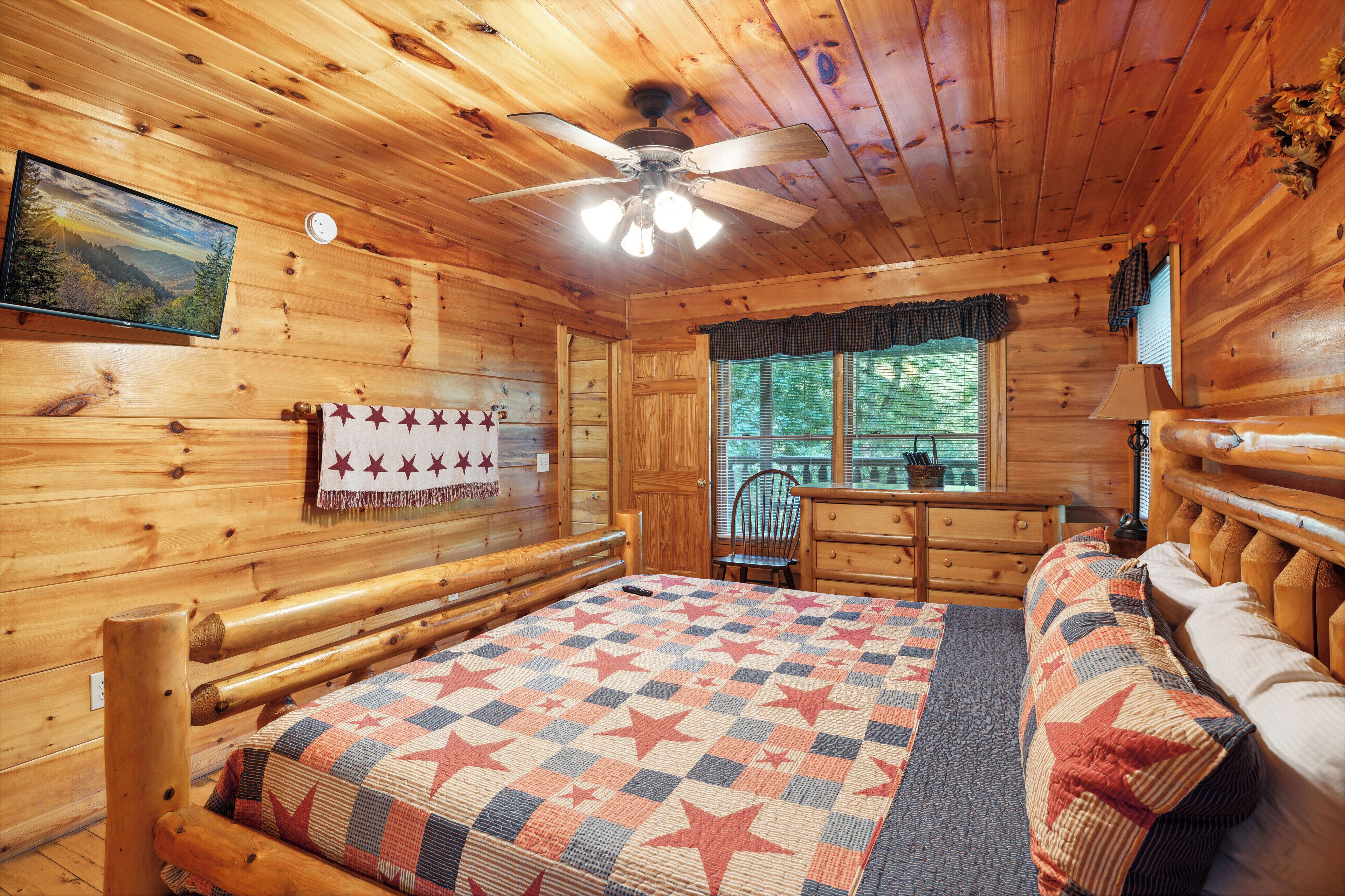 Una habitación de cabaña de madera con cama, una silla, un aparador y una ventana.
