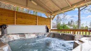 A hot tub area with a wooden deck and string lights. - Creekside Haven equals a Heavenly Escape (PIGEON FORGE)