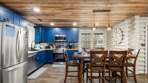 A modern kitchen with blue cabinets, stainless steel appliances, and a wooden ceiling.