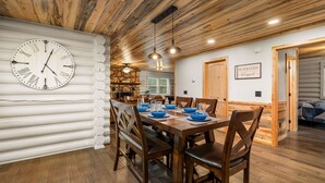 A wooden dining area with a clock, a stone wall, and a sign that reads "Be Our Guest."
