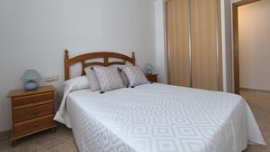 Une chambre à coucher avec un lit en bois, une table de chevet avec une lampe, une commode et une armoire.