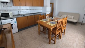Une cuisine compacte avec des meubles en bois, un four à micro-ondes encastré et un lave-linge.