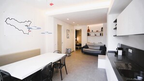 A modern kitchen with a dining area, a sofa, and a map on the wall. - Mandolino Apartment - Two Bedroom Apartment, Sleeps 5 (Syracuse)