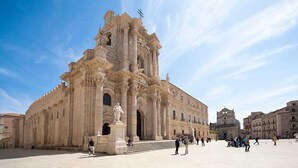 A historic building with classical architecture, including columns and statues, in a spacious square with people around. - Mandolino Apartment - Two Bedroom Apartment, Sleeps 5 (Syracuse)