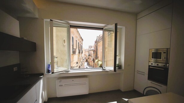 A kitchen with a window, a built-in oven, and a view of a narrow street. - Mandolino Apartment - Two Bedroom Apartment, Sleeps 5 (Syracuse)