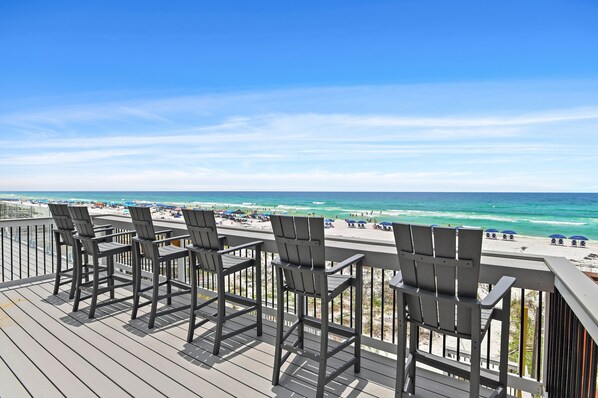 A deck with chairs overlooking a beach.