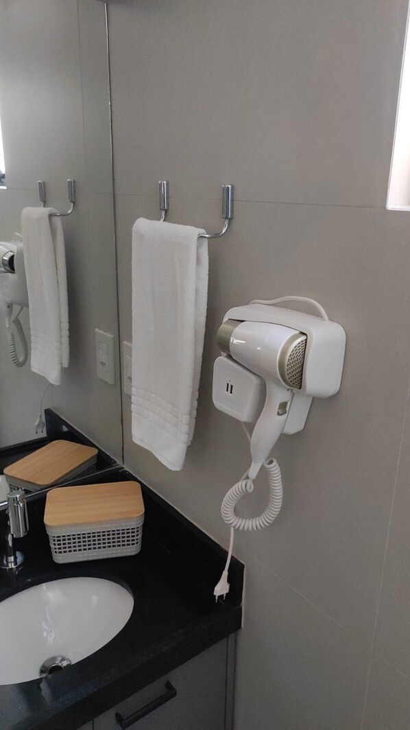 A bathroom with a sink, a hairdryer, and a mirror.