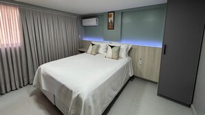 A hotel room with a bed, curtains, an air conditioner, and a wall-mounted artwork. - Bela Hospedagem -  303 Bauten Aurea  (João Pessoa)