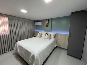Ein Hotelzimmer mit Bett, Vorhängen, einer Klimaanlage und einem Wandbild.