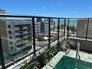 Un balcón con vista a una piscina, un edificio y una playa.