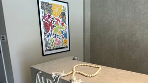 A reception desk with a framed artwork above it, a beaded necklace on the counter, and the word 'AREA' on the desk. - Bela Hospedagem -  303 Bauten Aurea  (João Pessoa)
