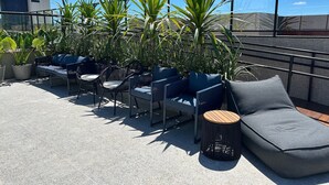 A rooftop terrace with outdoor seating, potted plants, and a clear blue sky. - Bela Hospedagem -  303 Bauten Aurea  (João Pessoa)