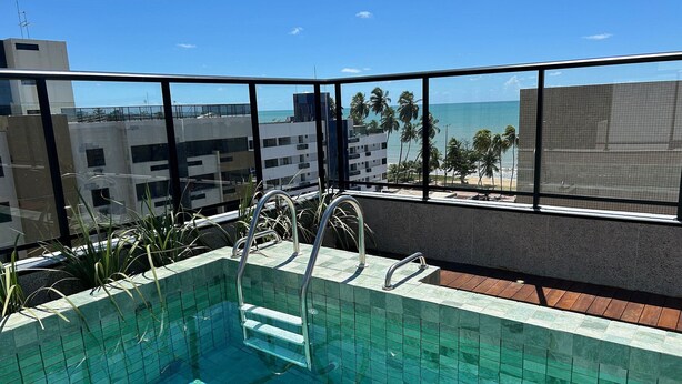 A rooftop pool with clear views of the ocean and palm trees. - Bela Hospedagem -  303 Bauten Aurea  (João Pessoa)