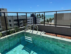Una piscina en la azotea con vistas despejadas al océano y palmeras.