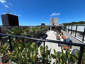 A rooftop terrace with outdoor seating, potted plants, and a view of the cityscape.
