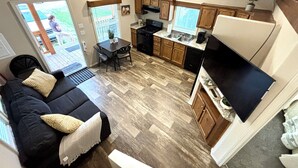 A compact kitchen with wooden cabinets, a dining table, and a black countertop. - Cozy Tiny Home Cabin by Hot Springs, Zip Line, Golf! (Ririe)