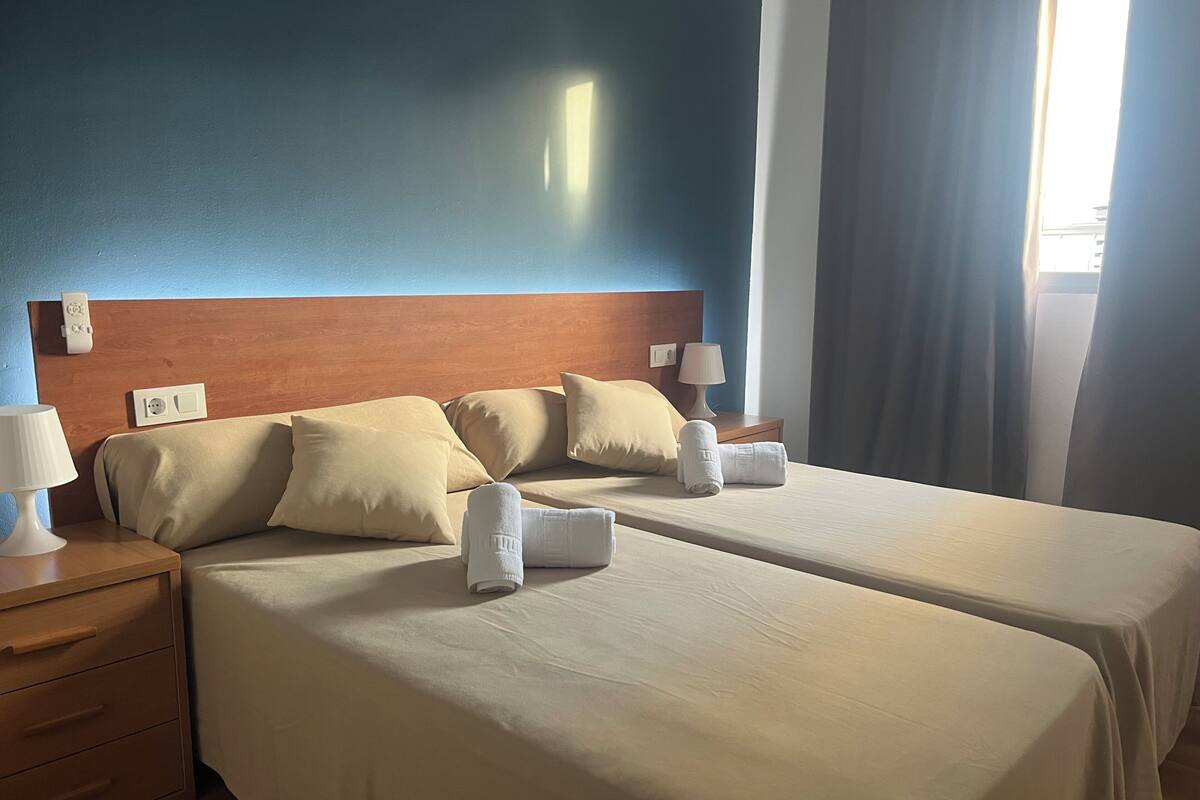Ein Hotelzimmer mit zwei Betten, einem Holzkopfende, Nachttischlampen und einem Nachttisch mit Lampe.