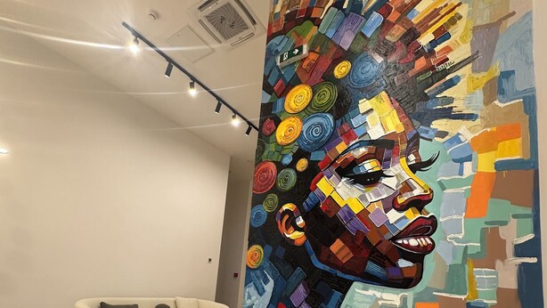 A modern interior with a colorful abstract mural, a white sofa, and a small round table. - Hotel Eleven (Sarajevo)