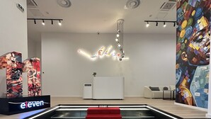A hotel reception area with a red carpet leading to the reception desk, a modern ceiling design, and a colorful abstract mural on the wall. - Hotel Eleven (Sarajevo)