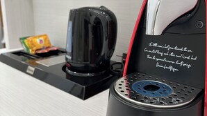 A modern coffee machine with a red and black design, a coffee pod holder, and a wall socket. - Hotel Eleven (Sarajevo)