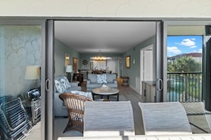 Un salon comprenant un canapé, une table basse et des fauteuils, un coin repas avec un lustre, et un balcon doté d’une balustrade.