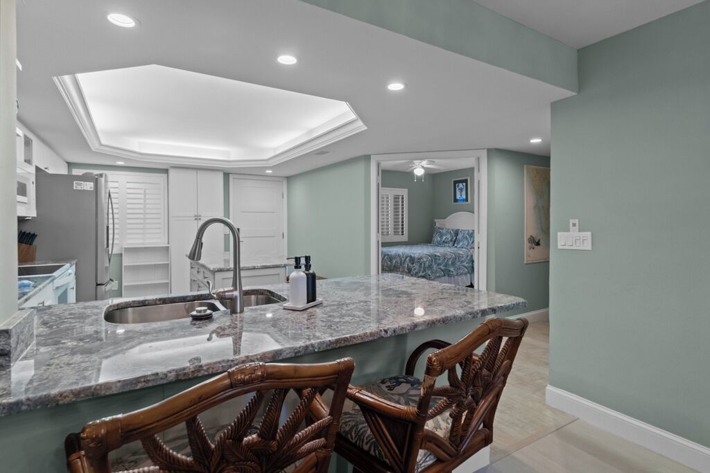 A modern kitchen with a central island, a built-in sink, and wooden chairs.