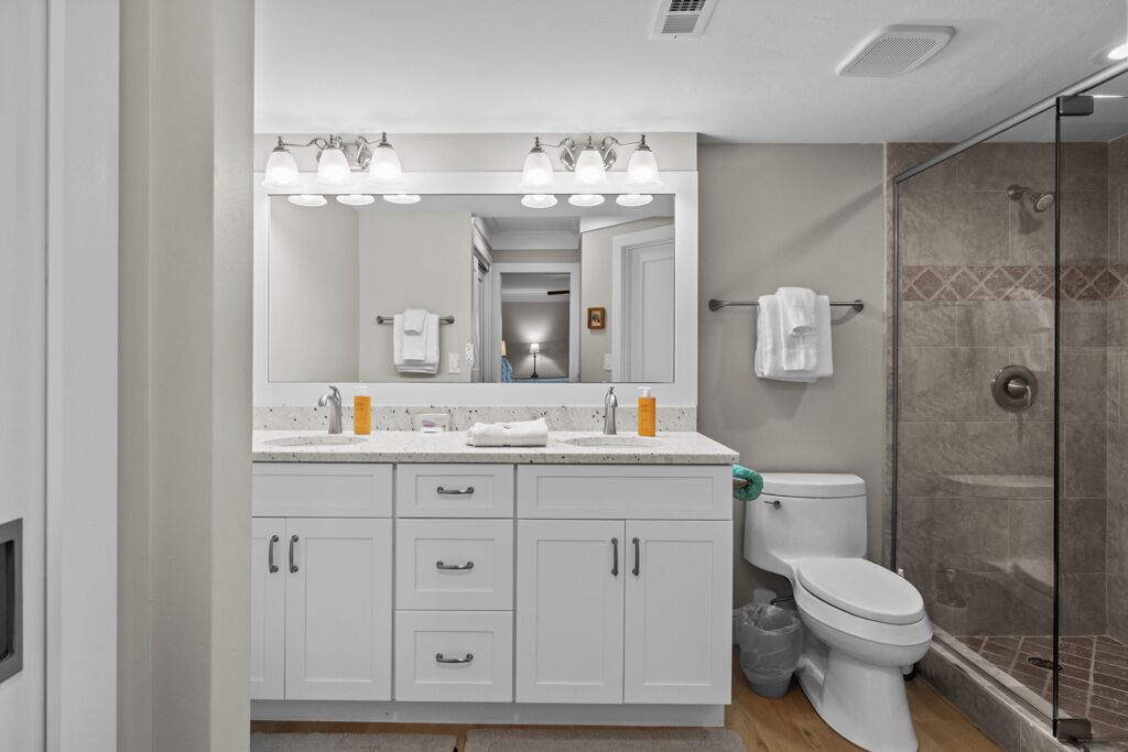 A modern bathroom with a glass shower enclosure, a white sink with a mirror above, and a toilet.