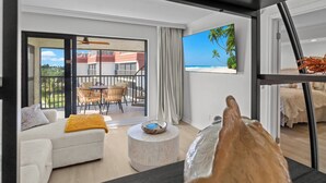 Ein modernes Wohnzimmer mit einer Couch, einem runden Couchtisch und einem an der Wand befestigten Fernseher.