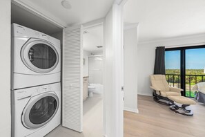 Un apartamento moderno con lavadora y secadora integradas, un balcón con vistas y un baño minimalista.