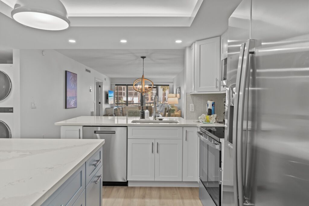 A modern kitchen with white cabinetry, a stainless steel refrigerator, and a central island.
