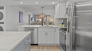 A modern kitchen with white cabinetry, a stainless steel refrigerator, and a central island.