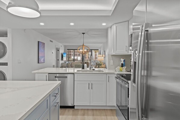 Una cocina moderna con armarios blancos, un refrigerador de acero inoxidable y una isla central.