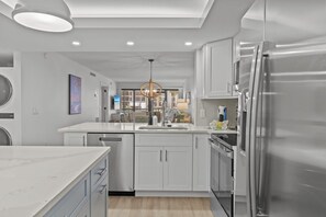 Une cuisine moderne avec des meubles blancs, un réfrigérateur en acier inoxydable et un îlot central.