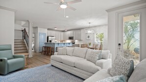 A spacious living room with a light-colored sofa, a blue patterned rug, and a ceiling fan.