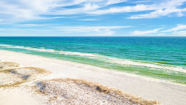 A beach with clear blue water and a sandy shore.