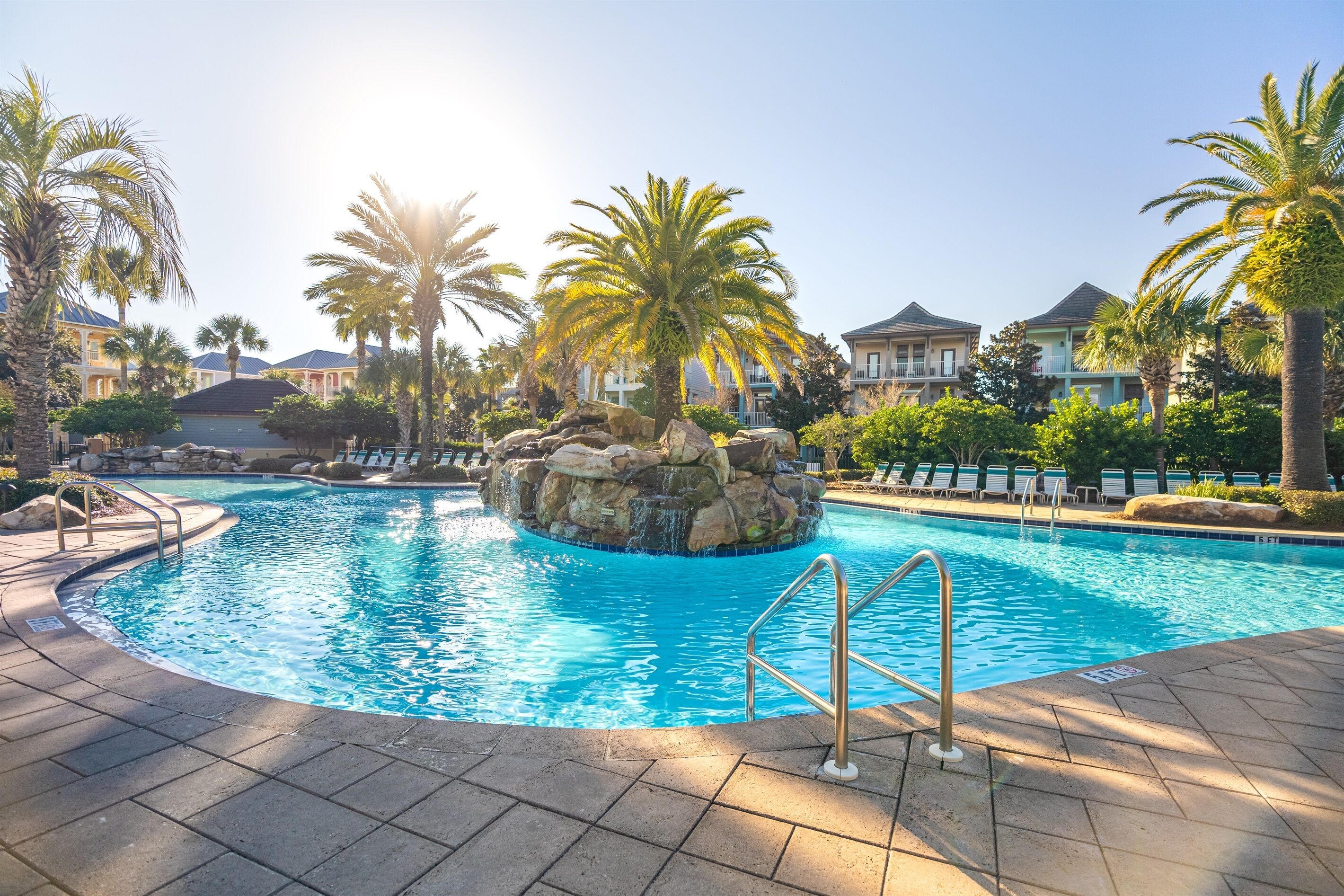 Ein Pool mit Felsen und Palmen, eingebettet in eine Ferienanlage.