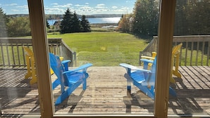 Une terrasse avec deux chaises Adirondack bleues donnant sur une pelouse et un lac.