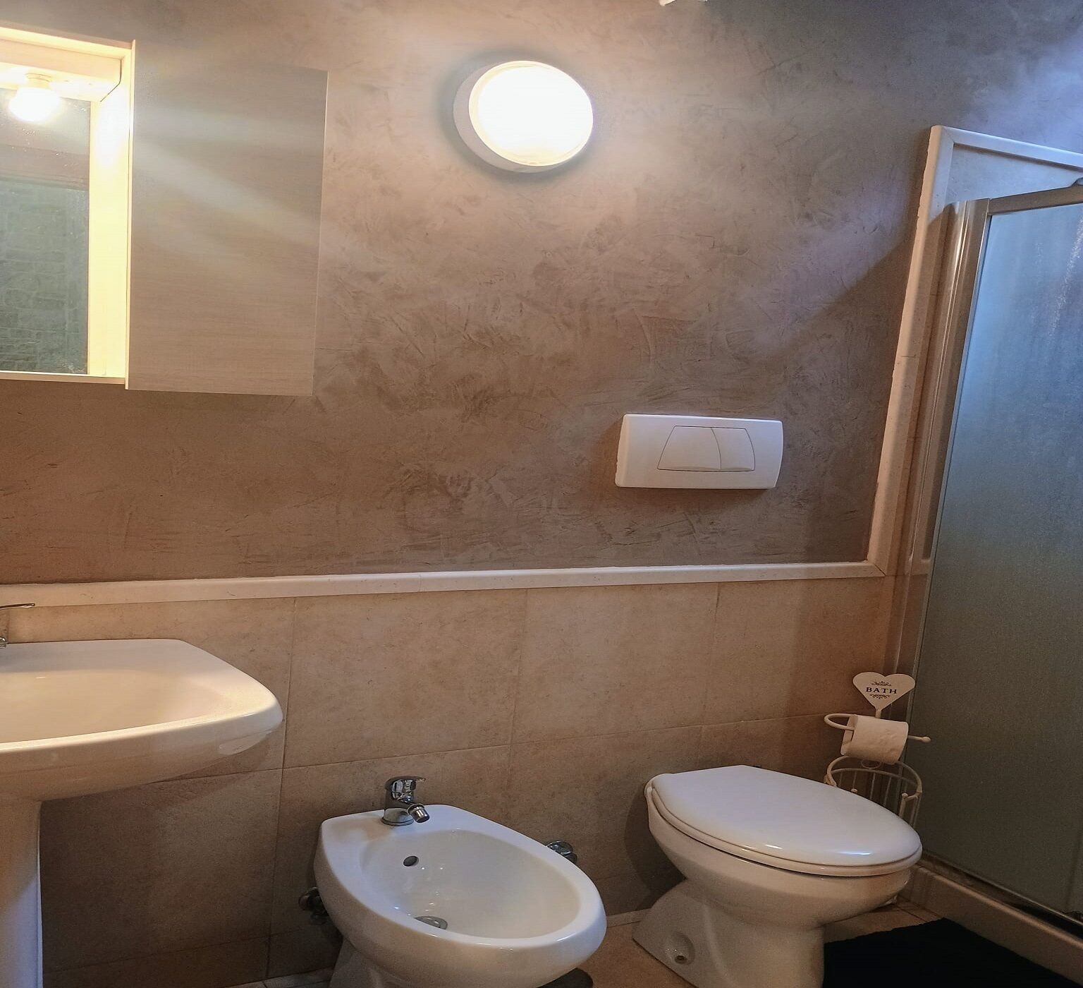 Un baño con lavamanos, bidé, inodoro y espejo.
