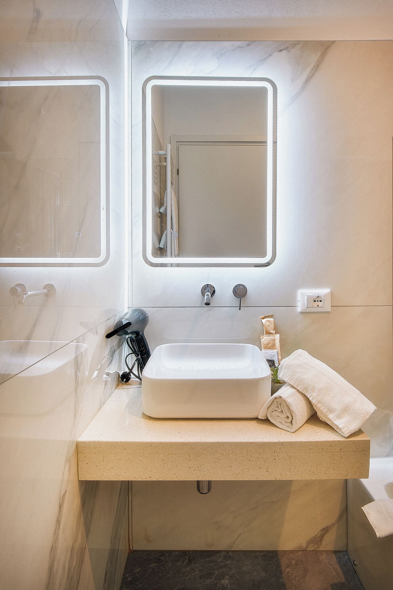 Une salle de bain moderne avec un grand miroir, un lavabo et un espace douche.