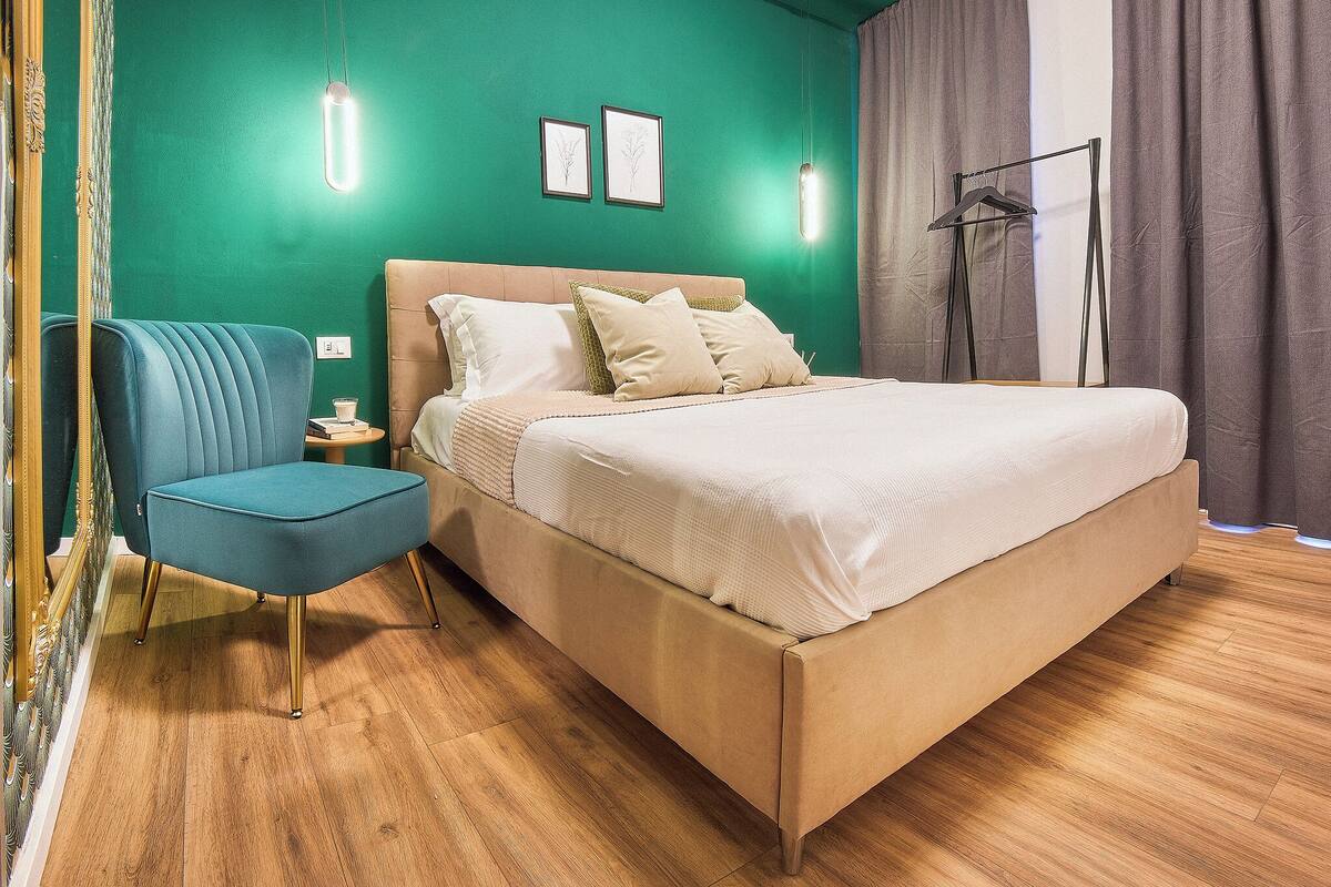 Ein Schlafzimmer mit Bett, Nachttisch, Stuhl und einer Hängelampe.