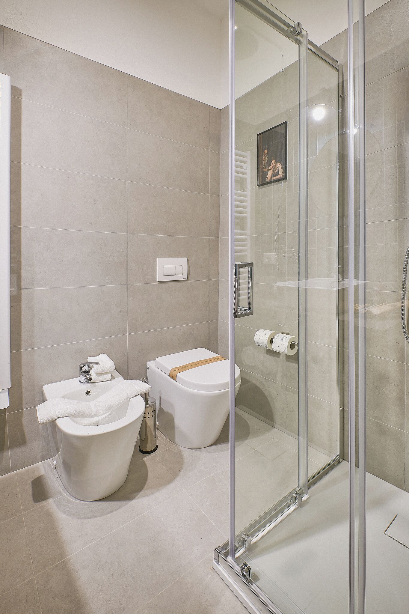 A modern bathroom with a glass-enclosed shower, two sinks, and a toilet.