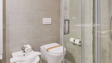 A modern bathroom with a glass-enclosed shower, two sinks, and a toilet.