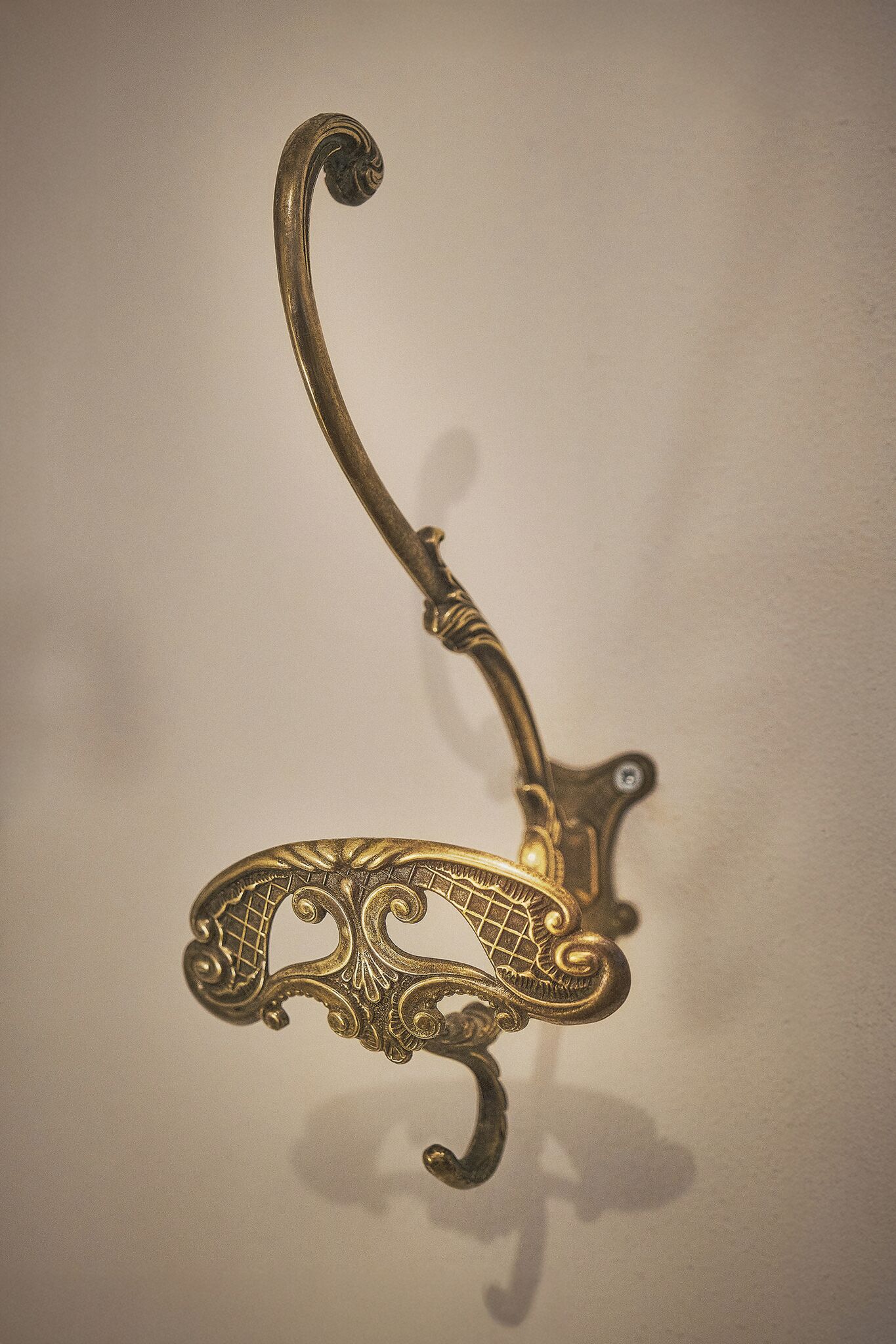 A brass wall hook with an ornate design.