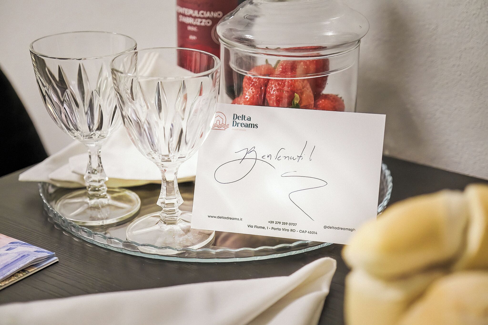 A table with two clear glass goblets, a card with a signature, and a jar of strawberries.